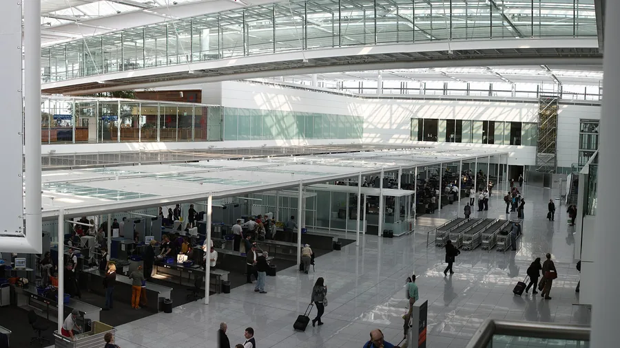 Sikkerhetskontrollen på en stor flyplass sett ovenfra, med reisende i kø ved kontrollpunktene